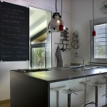 Amaxing Glass Stools in the Kitchen with White Island and Black Countertop under Small Red Lamps