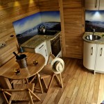 Simple Wooden House Kitchen and Fold Away for the two People facing the Brown Wooden Wall