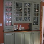 Attractive Shelving inside Wooden Cabinet with Glass Doors and Grey Color using Wooden Top beside Brown Painted Wall