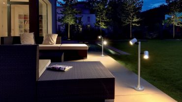 Contemporary Outdoor Lighting Fixtures and Dark Wicker Sofa Chaise in Cozy Patio facing Grass Yard