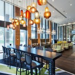 Modern Pendant Lighting Fixtures above Open Dining Area with Long Dark Bar Table and Comfortable Stools