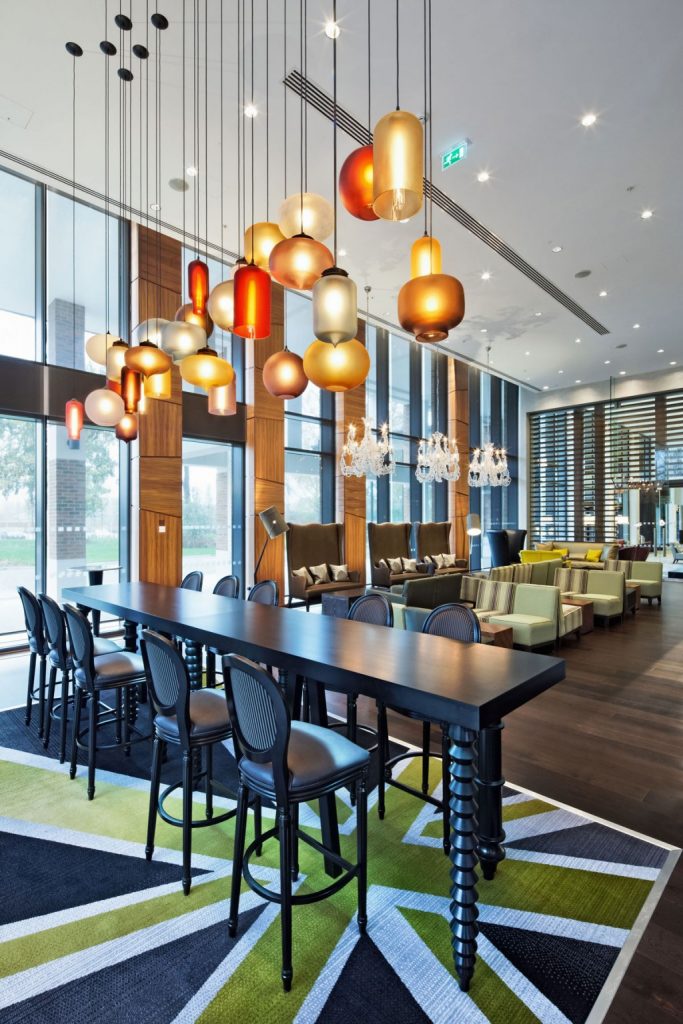 Modern Pendant Lighting Fixtures above Open Dining Area with Long Dark Bar Table and Comfortable Stools