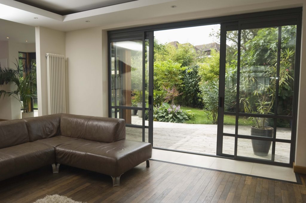 Stylish Open Up Sliding Glass Doors near Brown Leather Sofa Set at Living Room