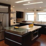 Luxurious Glass Extended Table Contiguous Fridge Enlightened by Kitchen Ceiling Lights