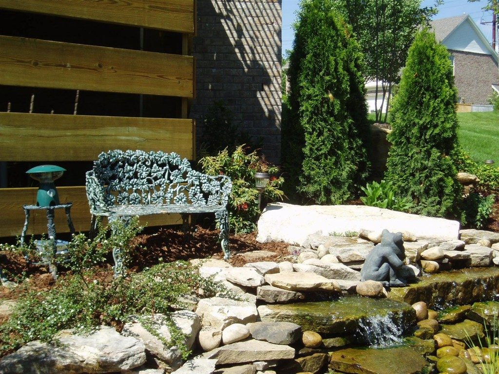 Unique Bench and Side Table facing Appealing Stone Waterfall Pool in Stunning Gardens Decorating Ideas