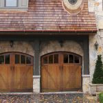 Rustic Carriage Style Garage Doors with Two Lamp on Brick Wall plus Fresh Plant