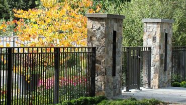 Inspiring Entrance Garden Applying Stone Brick Gate Combined with Black Metal Fence Ideas