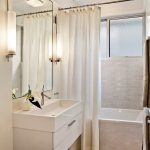 White Updated Bathroom in Tiny Size with Large MIrror and White Bathing Tub and Light Curtains